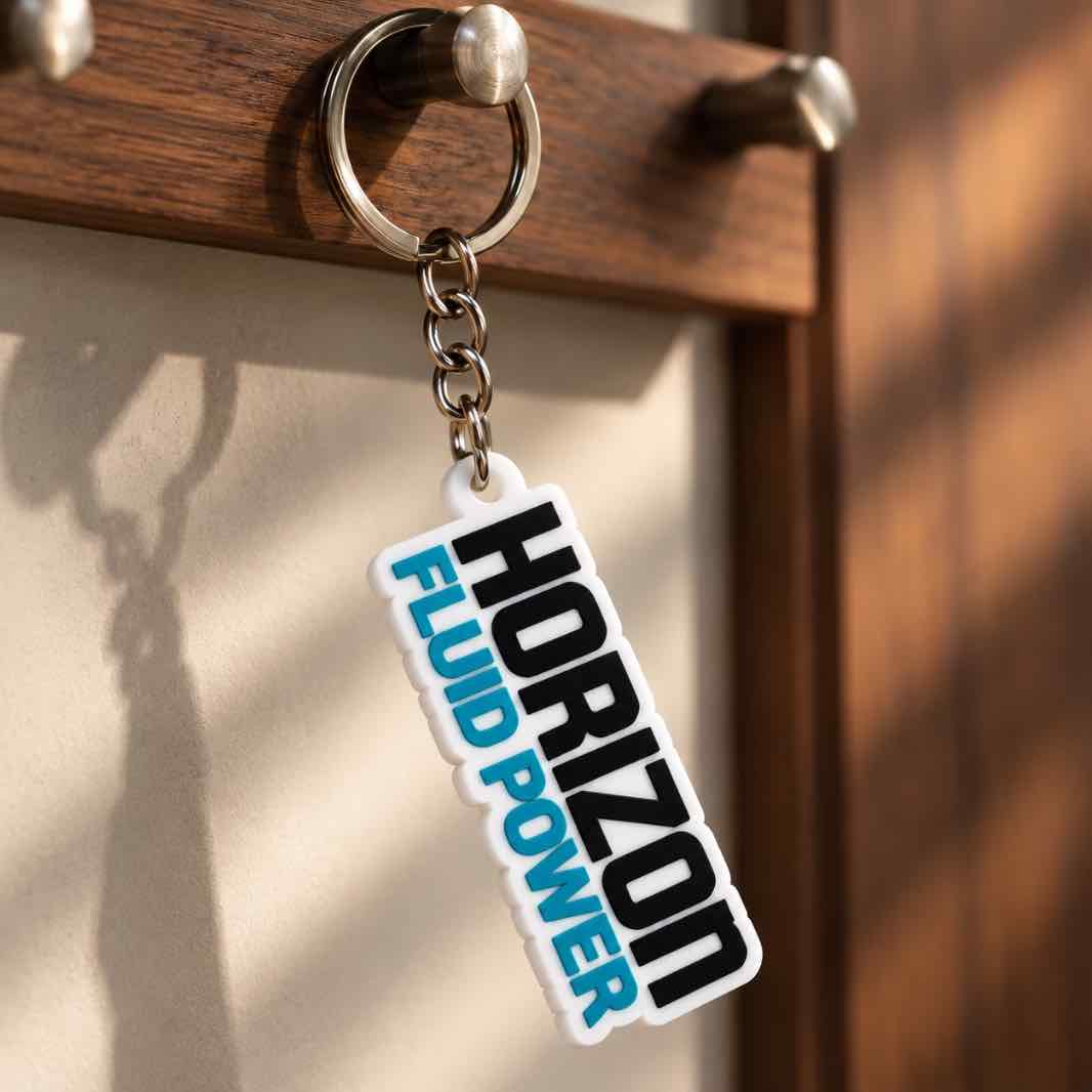 Personalized white Horizon Fluid Power acrylic keychain with black and turquoise lettering on a warm wooden key holder