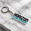 Custom Horizon Fluid Power acrylic keychain with black and turquoise lettering placed on a white marble surface with silver keyring