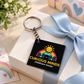 Curious Minds ChildCare Center personalized keychain with black acrylic tag and silver chain displayed on a white gift box with pastel ribbon