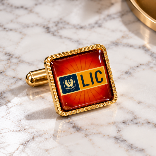 Single LIC gold cufflink with red-orange glossy face displayed on white marble in a luxury product setting