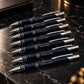 customized navy blue ballpoint pens with gold YOUR LOGO branding arranged elegantly on a black marble surface, showcasing premium personalized pens for corporate gifting, executive gifts, and branded business accessories.