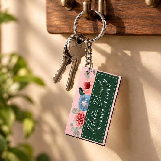 Personalized pink floral acrylic keychain hanging with silver keys, featuring a custom makeup artist design and elegant green panel on a wooden key holder