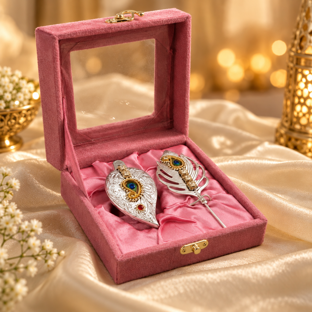 Pink velvet jewelry gift box with two ornate silver and gold decorative pieces displayed on elegant cream silk fabric.