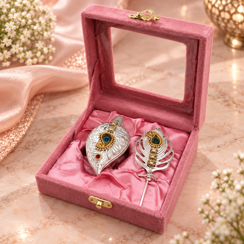 Pink velvet jewelry gift box featuring two ornate silver and gold decorative pieces with blue and red gemstone detailing on satin lining.
