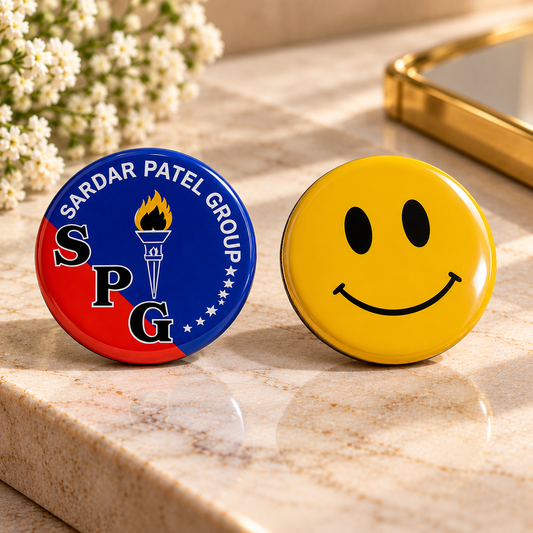 Sardar Patel Group custom round badge and yellow smiley badge displayed together on a premium marble surface