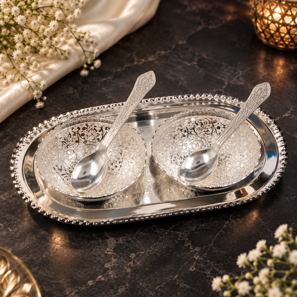 Decorative silver bowls filled with almonds, cashews, pistachios and raisins placed on an engraved silver tray