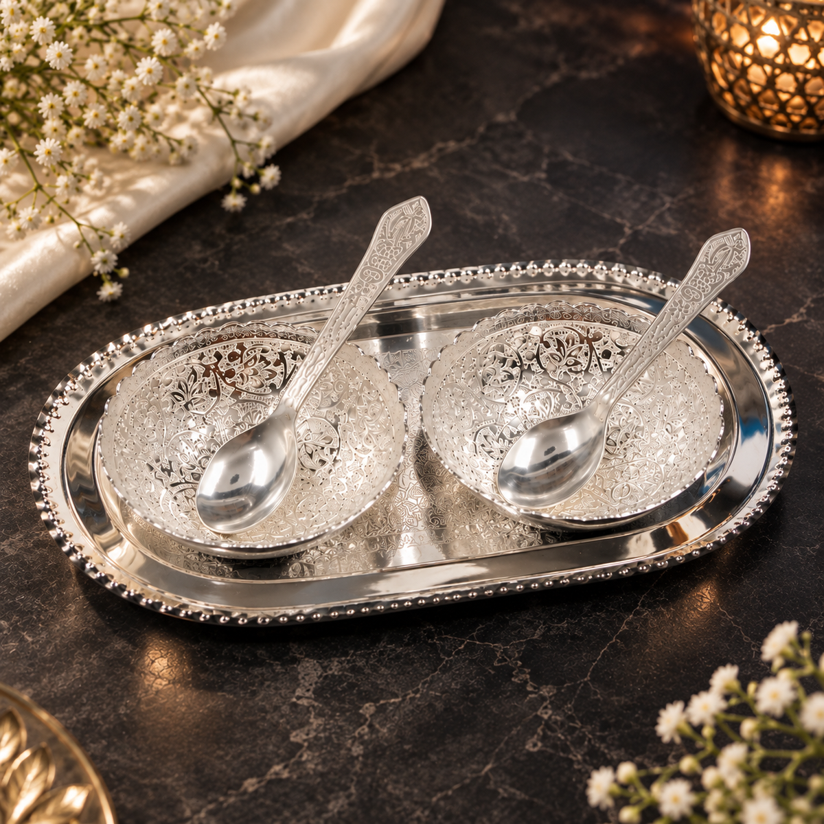 Decorative silver bowls filled with almonds, cashews, pistachios and raisins placed on an engraved silver tray