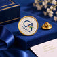 Round CA India brooch with gold finish showcased on a royal blue velvet background