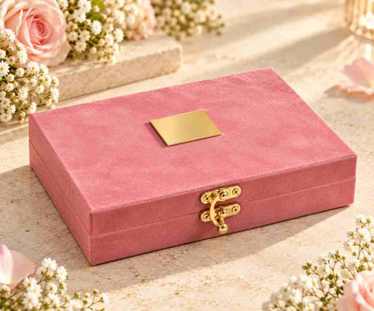 Pink velvet jewellery gift box with gold clasp on cream pedestal with flowers
