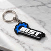 A black and blue MOTION SYSTEMS TECHNOLOGY keychain with a silver metal split ring, resting on a white marble surface.