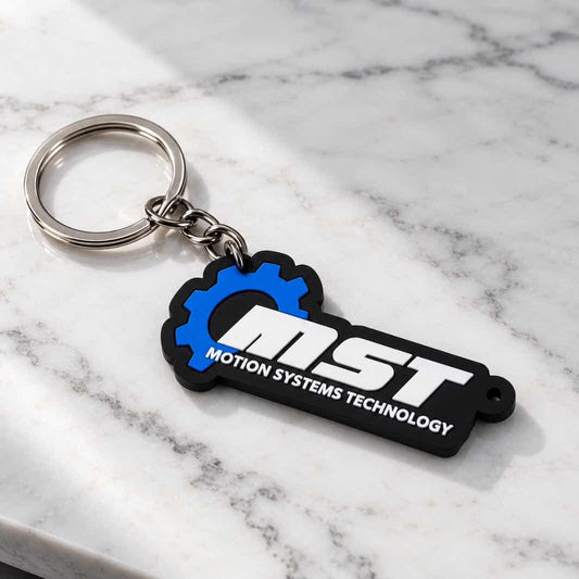 A black and blue MOTION SYSTEMS TECHNOLOGY keychain with a silver metal split ring, resting on a white marble surface.