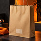 Brown kraft paper carry bag photographed against a dark charcoal and burnt orange backdrop in a premium editorial setup