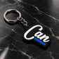 A black and white rubber keychain with the text 'Can DOGSAN' in white and blue, attached to a silver metal key ring, resting on a black marble surface.